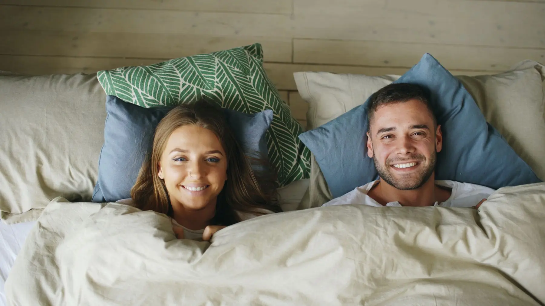 Lächelndes Paar liegt entspannt im Bett